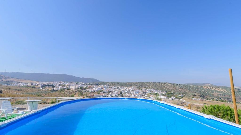 une grande piscine bleue avec vue sur la ville dans l'établissement Cortijo La Umbria Villanueva de Algaidas by Ruralidays, à Villanueva de Algaidas