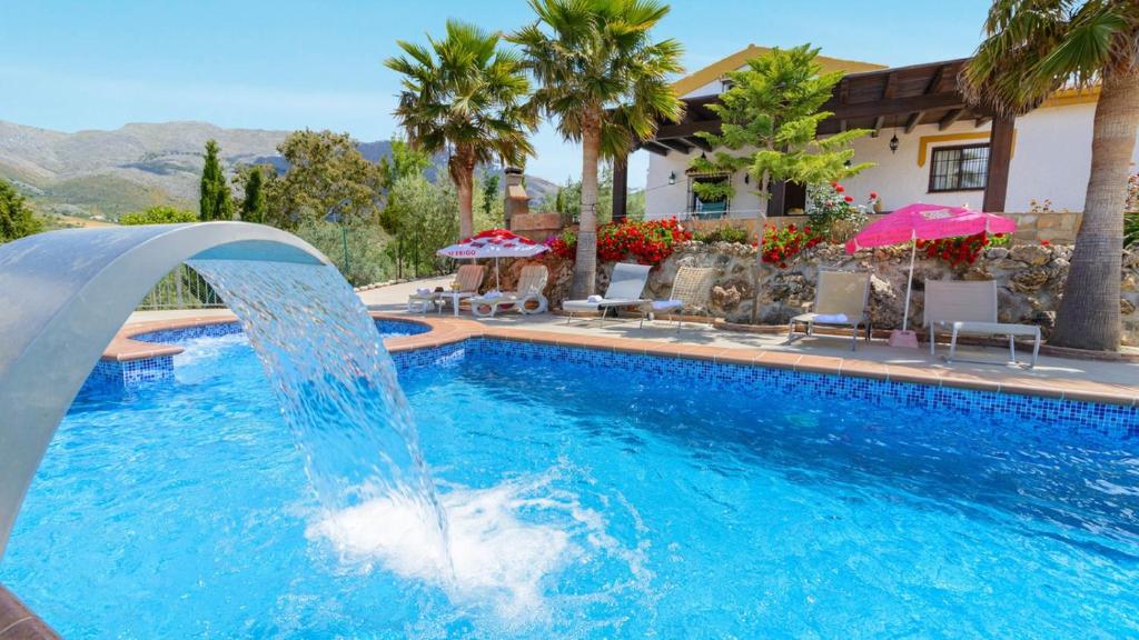 a pool with a water fountain in front of a house at Casa Las Lomas de San Rafael Periana by Ruralidays in Periana