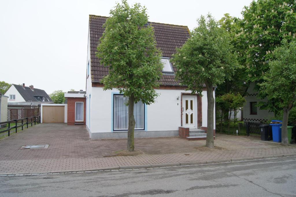 a white house with two trees in front of it at Ferienwohnungen Buchholz in Büsum