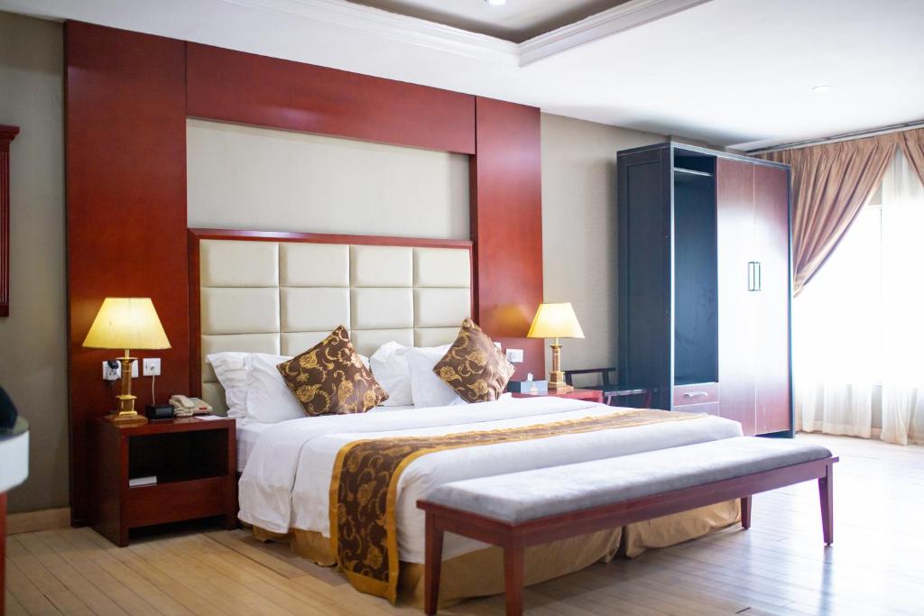 a bedroom with a large bed and a large window at Hotel Sunshine Enugu in Enugu