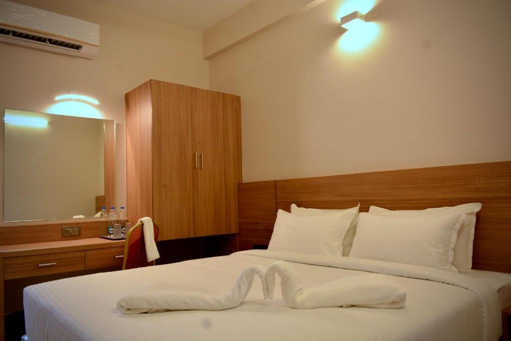 a hotel room with two beds and a mirror at The First Light Inn in Kanchipuram