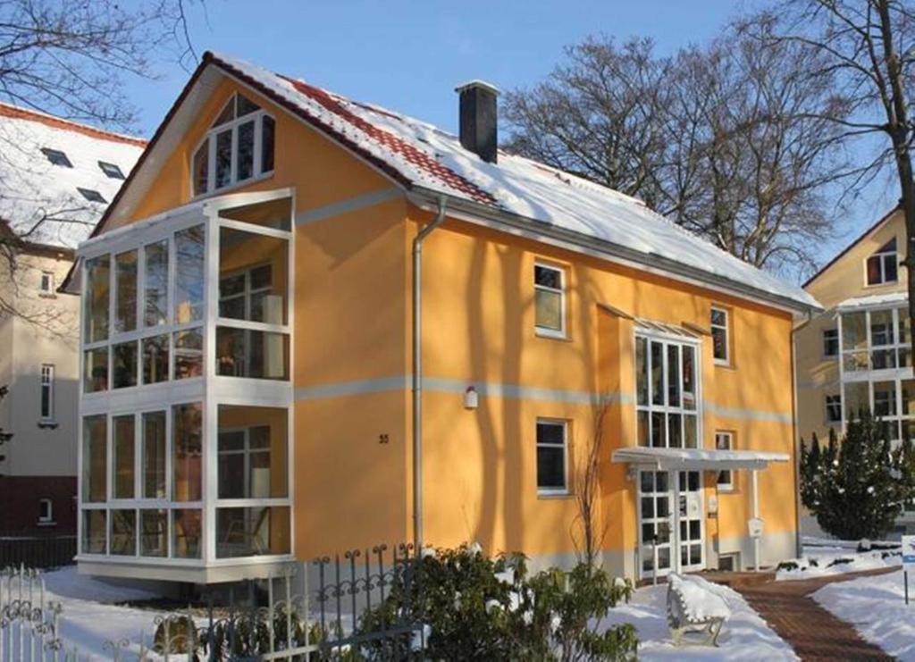 una casa naranja con ventanas blancas en la nieve en Ostseepark Waterfront Galeone 41, en Bansin