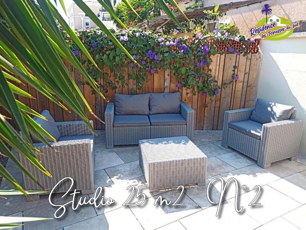 un patio con mobili in vimini e una recinzione con fiori di Villadali-fr Appart Hôtel TOULON Clim, Wifi, Terrasse, Cuisine Parking Gratuit a Tolone