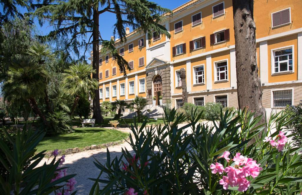 un bâtiment avec des palmiers et des fleurs dans un parc dans l'établissement LH Hotel Excel Roma Montemario, à Rome