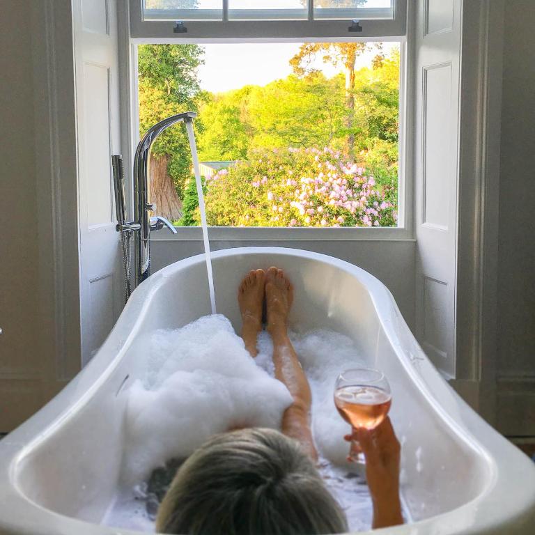 a person sitting in a bath tub with a glass of wine at Eithinog Hall in Welshpool