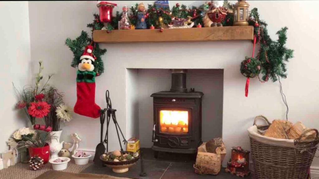 una sala de estar con chimenea y un almacén de Navidad encima en PondeROSEa Cottage Free Gated Parking M1 & City location, wood stove, en Lisburn