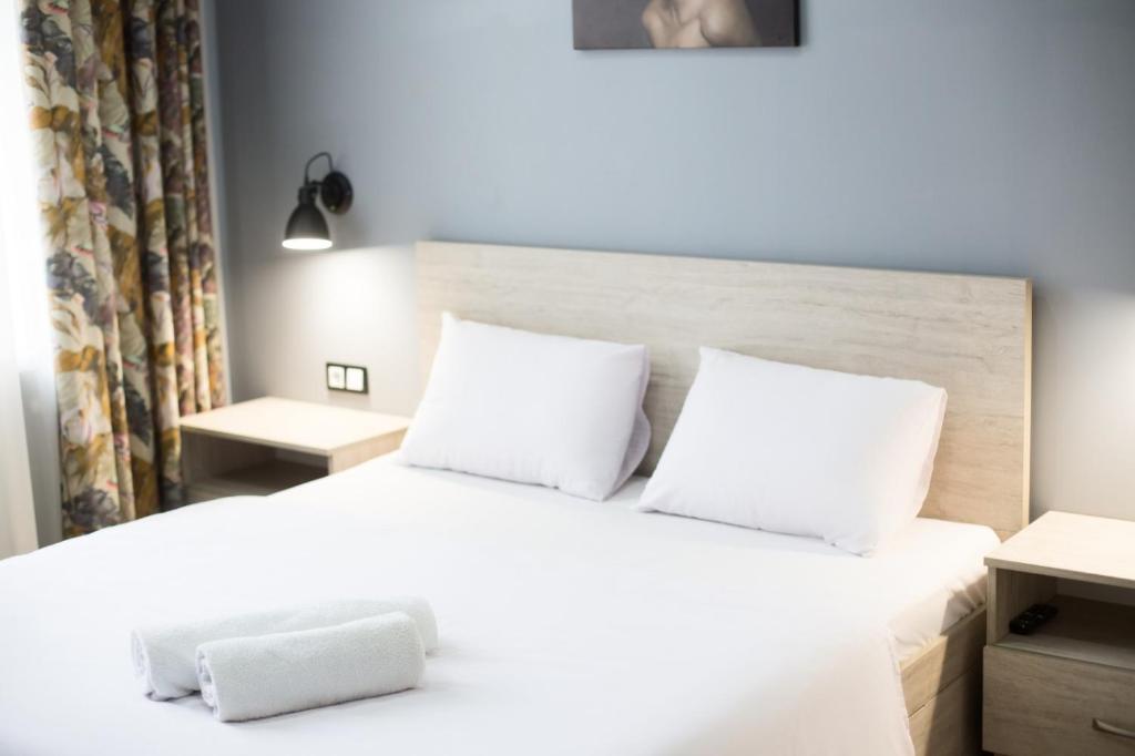 a bedroom with a white bed with two pillows at Lviv4U in Lviv