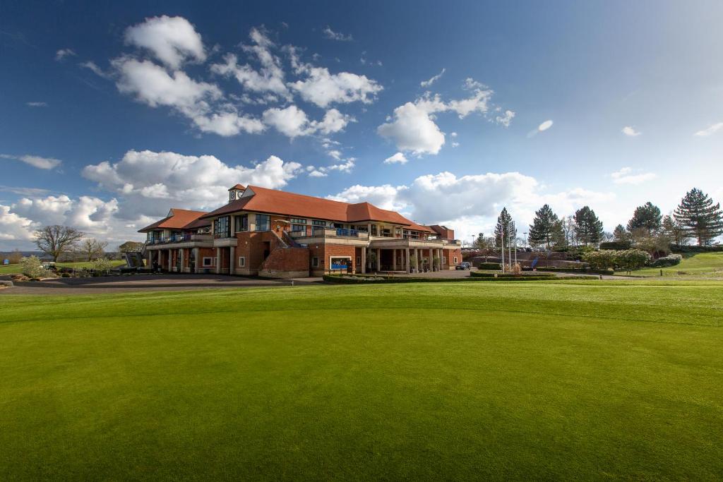 a large house on a golf course with a green at The Oxfordshire Golf & Spa Hotel in Thame