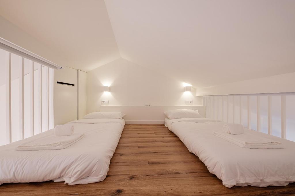 a row of beds in a room with white walls at BOUTIQUE Rentals- ATTICO Luxury Design-Ocean views in Porto