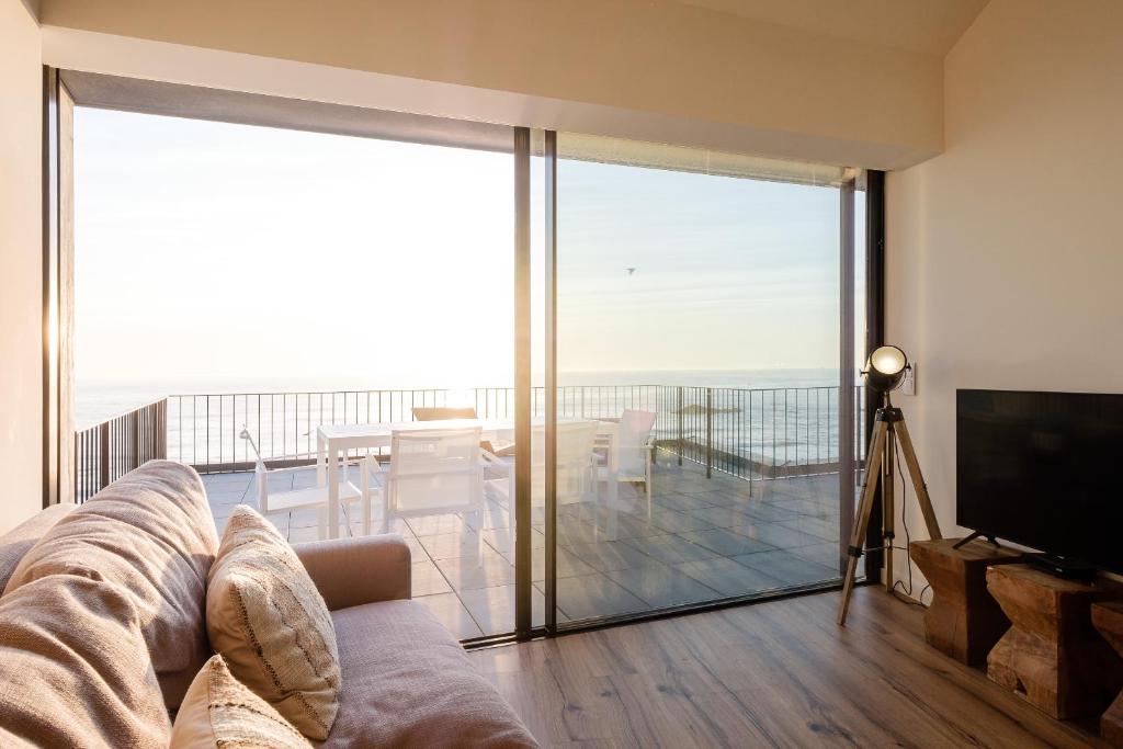 a living room with a couch and a tv and a balcony at BOUTIQUE Rentals- ATTICO Luxury Design-Ocean views in Porto