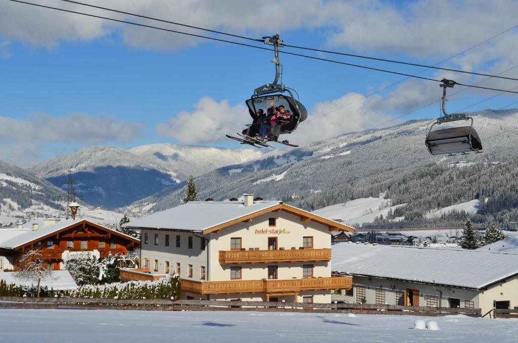 eine Person, die mit einem Skilift über ein Gebäude fährt in der Unterkunft Hotel Starjet in Flachau