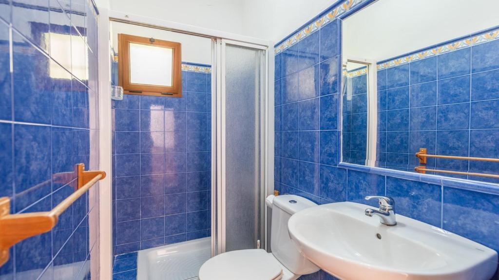 W wyłożonej niebieskimi kafelkami łazience znajduje się toaleta i umywalka. w obiekcie Finca Salrima Alora by Ruralidays w mieście Alora