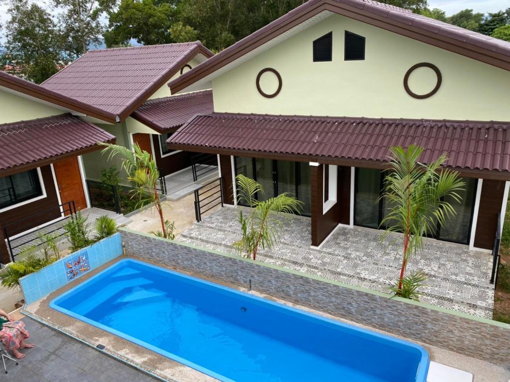 a house with a blue swimming pool in front of it at Piumsuk Villa in Satun
