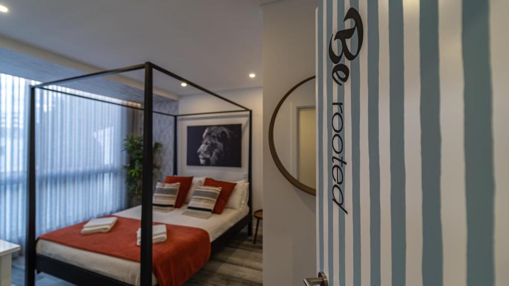a bedroom with a canopy bed and a mirror at Plan Be GuestHouse in Faro