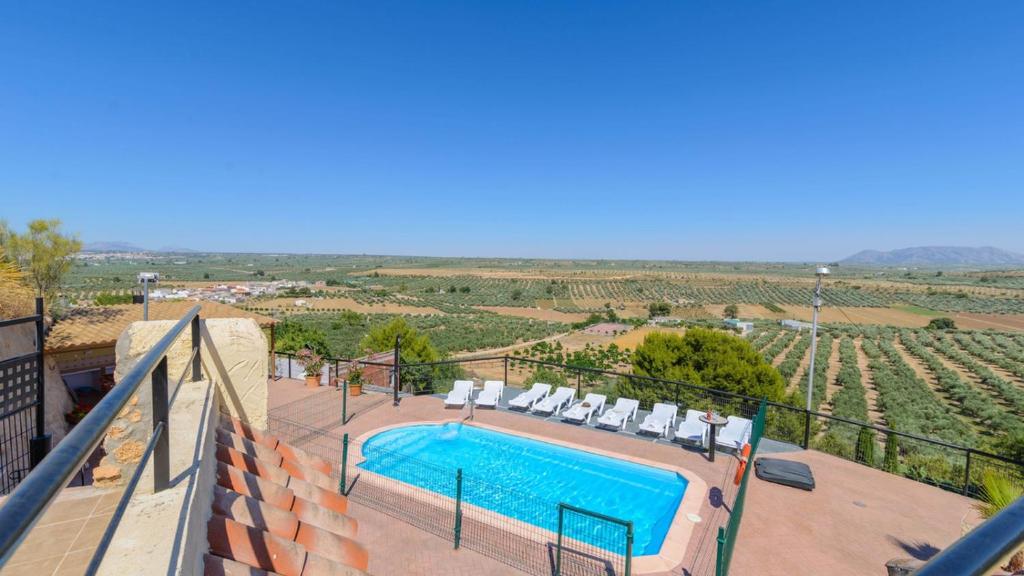 una piscina con sillas y vistas a un viñedo en Cuevas El Mirador Pozo Alcon by Ruralidays en Pozo Alcón