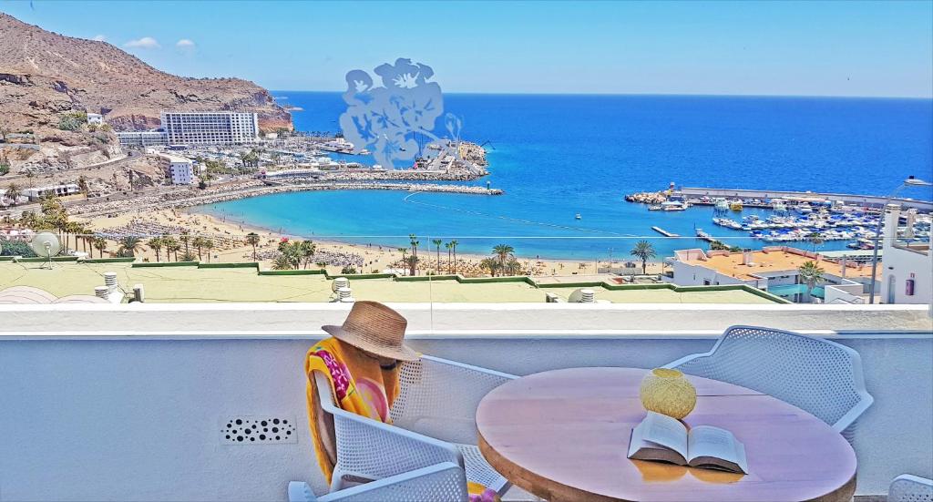 a woman sitting at a table with a view of the ocean at Apartamentos Gelimar in Puerto Rico de Gran Canaria
