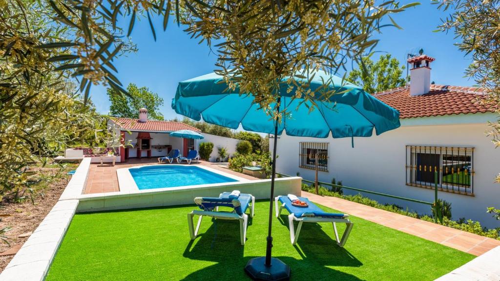 un patio con piscina, 2 sillas y sombrilla en Casa Alejo Antequera - La Higuera by Ruralidays, en Antequera