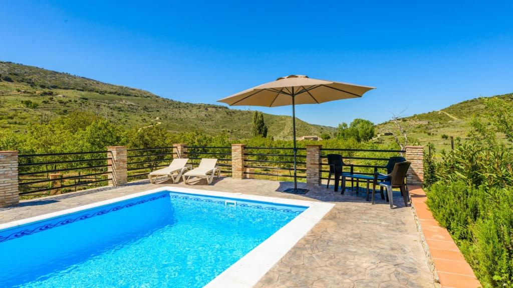 uma piscina com um guarda-sol, uma mesa e cadeiras em Casa Los Linarejos Ronda by Ruralidays em Ronda