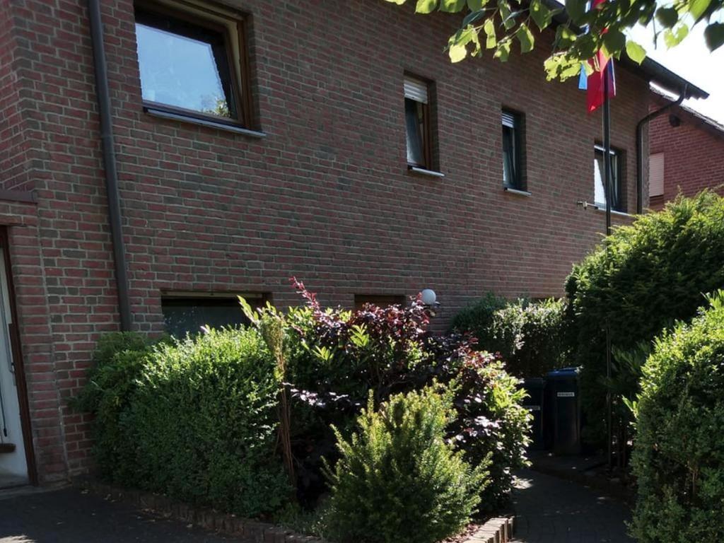 a brick building with bushes and flowers in front of it at Ferienwohnung Mauer in Neuenrade