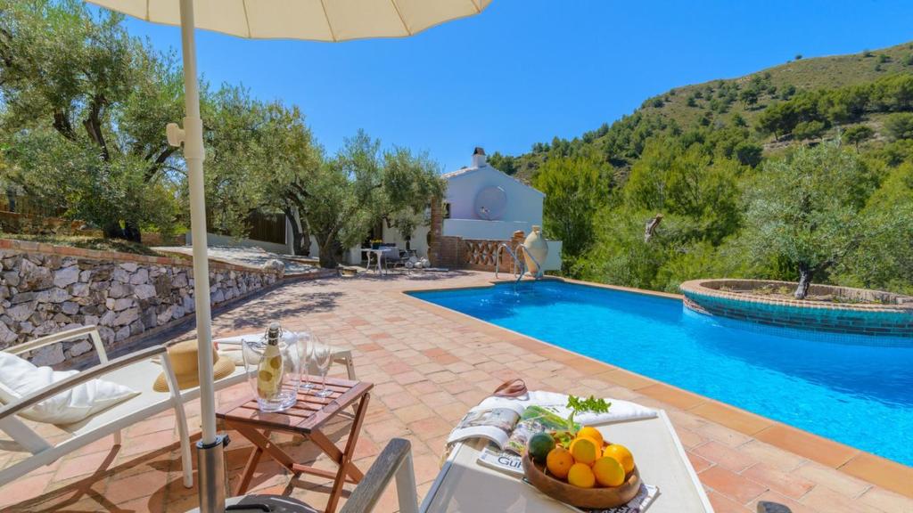 Cette villa dispose d'une piscine avec une table et des chaises. dans l'établissement Finca Colores en el Viento Frigiliana by Ruralidays, à Frigiliana