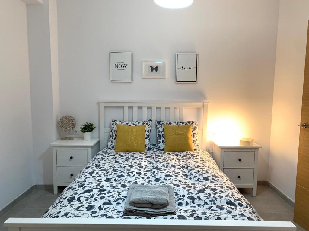 a white bedroom with a bed with yellow pillows at UIM Mediterraneo PB Aragon B Wifi in Puerto de Sagunto