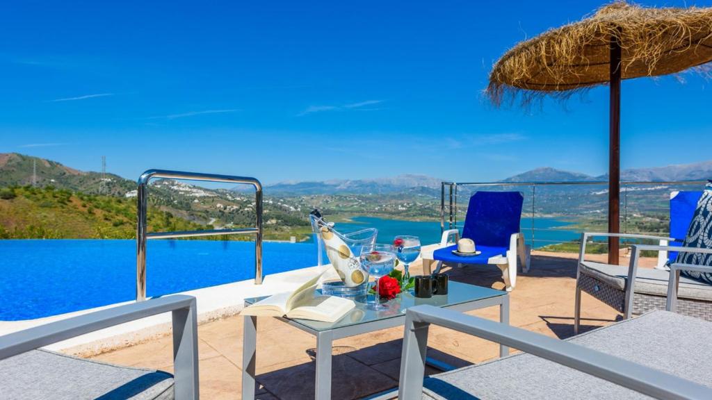 un patio con mesa y sillas y vistas al agua en Villa Adelfas Vinuela by Ruralidays, en Viñuela