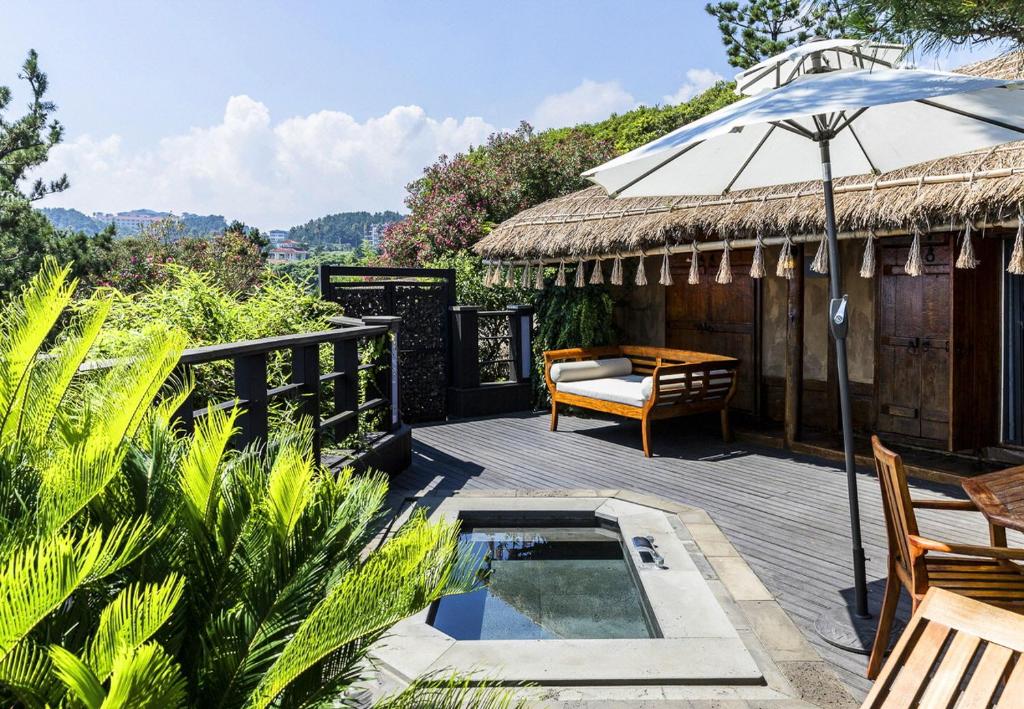 um deque com uma piscina e um guarda-sol em The Seaes Hotel & Resort em Seogwipo