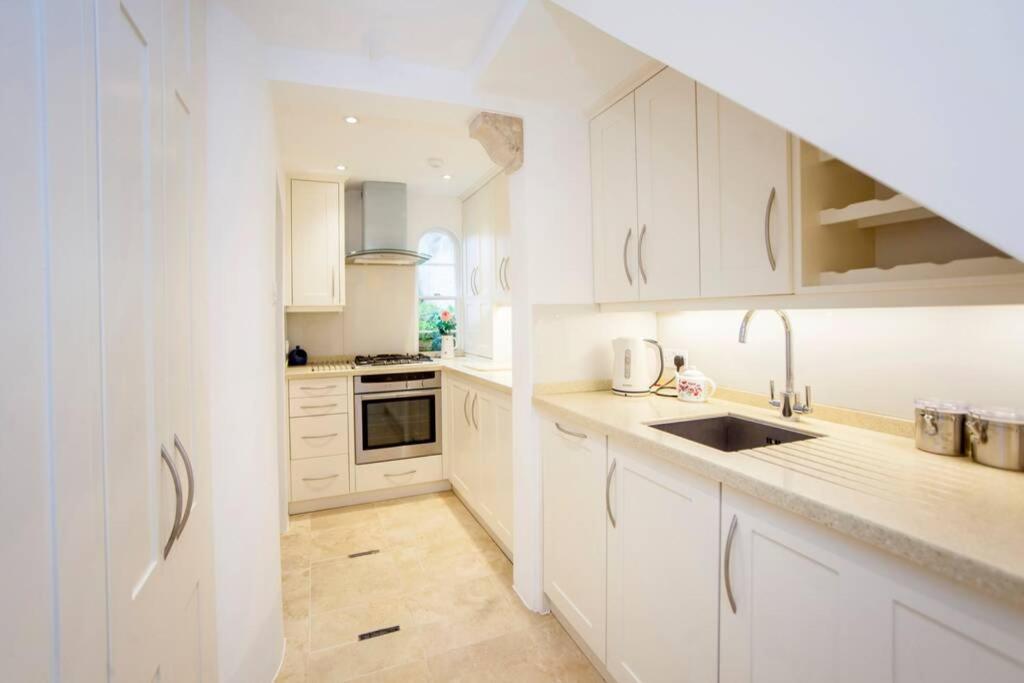 een witte keuken met witte kasten en een wastafel bij The Bath Retreat in Bath