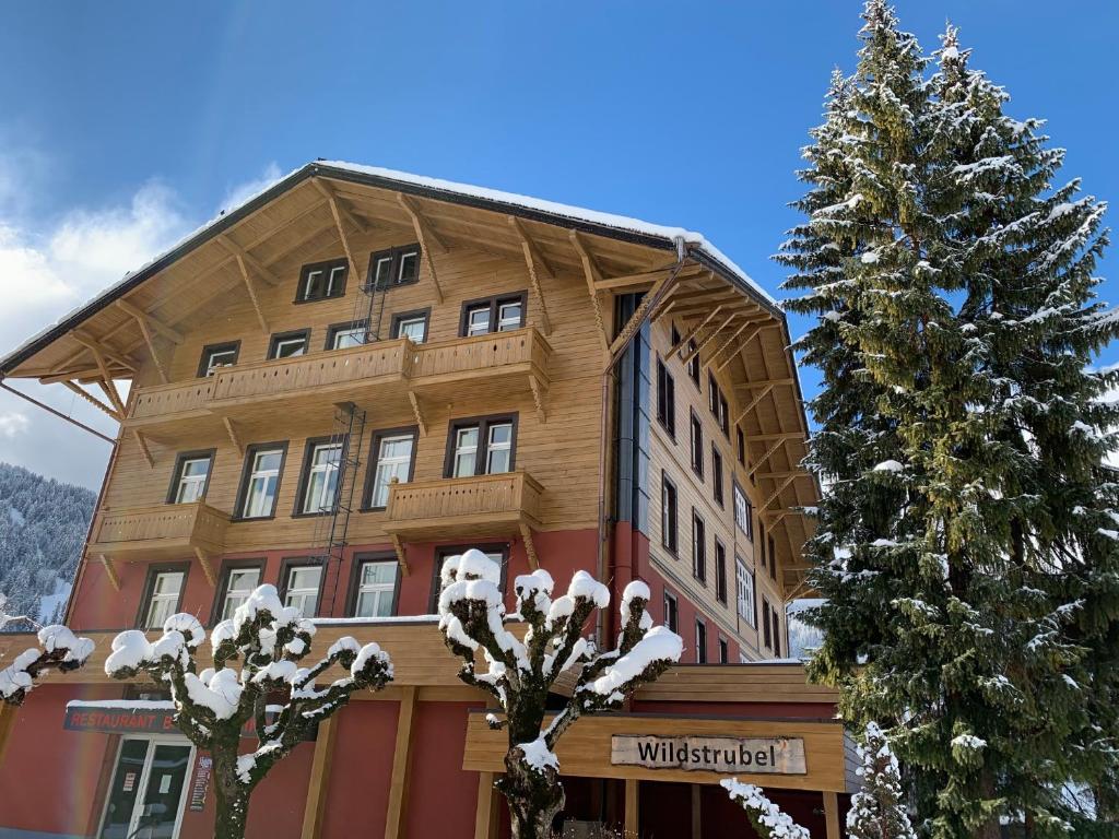 un gran edificio de madera con un árbol de Navidad delante de él en Sporthotel Wildstrubel, en Lenk