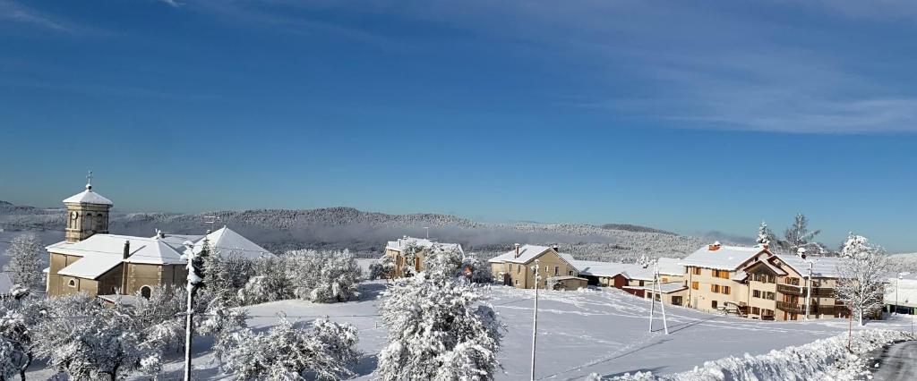 une ville recouverte de neige avec un bâtiment et une église dans l'établissement Le Relais Nordique, à Giron