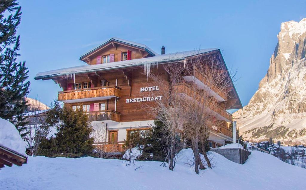 a large wooden building with snow on the ground at Hotel Gletscherblick Grindelwald in Grindelwald