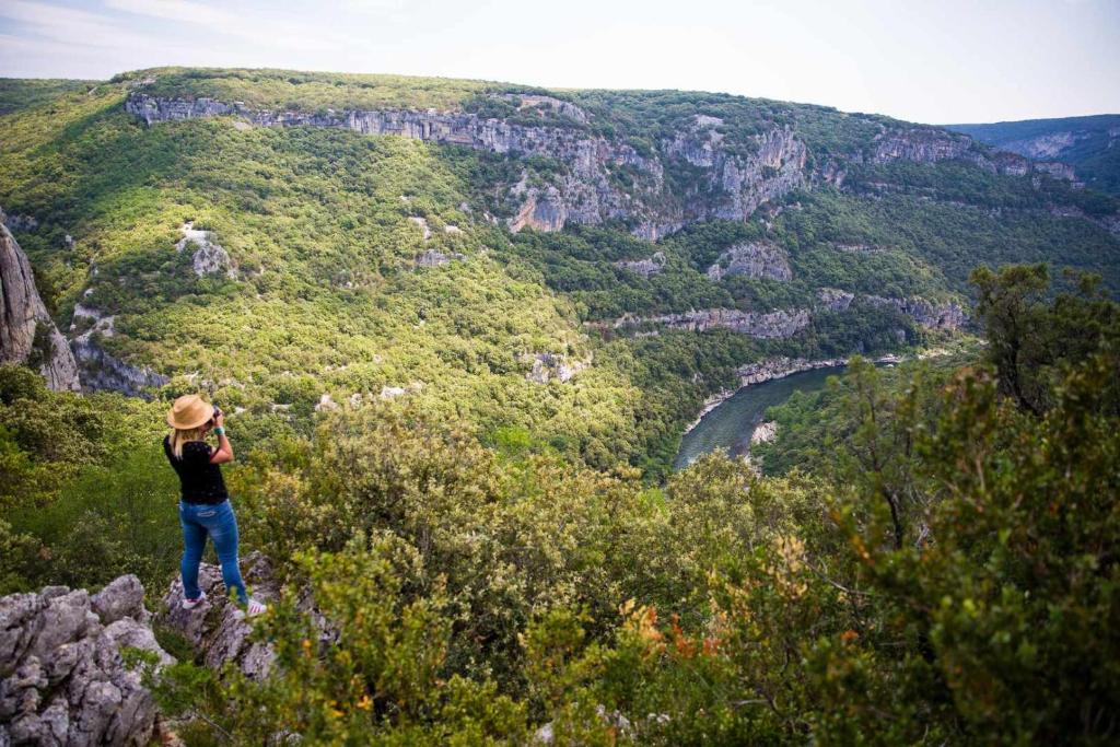 a person standing on a mountain looking at a valley at Camping Mille Étoiles in Labastide-de-Virac