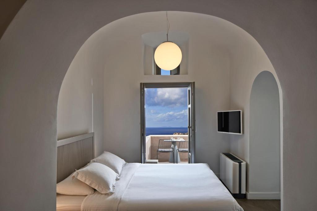 a bedroom with a bed with a view of the ocean at Old Castle Oia in Oia
