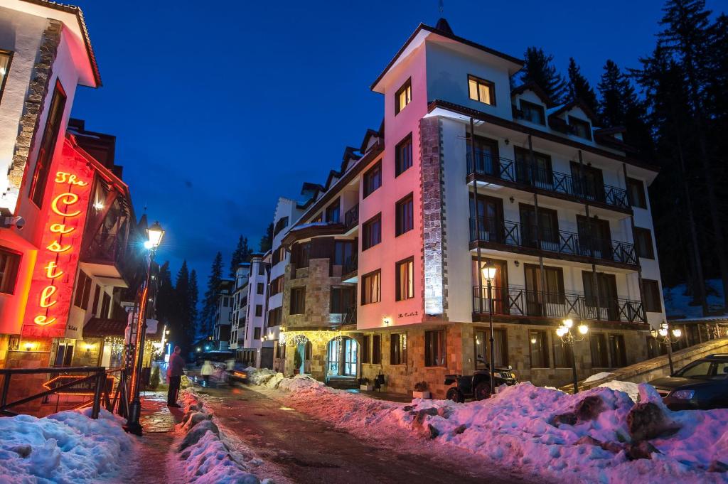 un groupe de bâtiments recouverts de neige dans une rue la nuit dans l'établissement Studio - Apartments Castle Complex 2, à Pamporovo