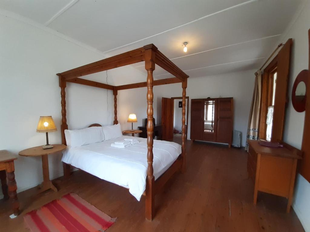 een slaapkamer met een groot bed met een houten baldakijn bij Quince&Cottage in Nieu-Bethesda