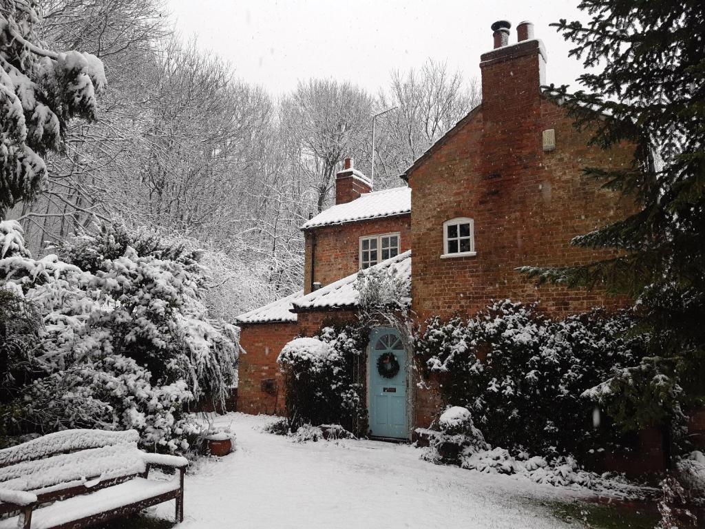 ceglany dom z niebieskimi drzwiami w śniegu w obiekcie Sunny Cottage w mieście Grantham