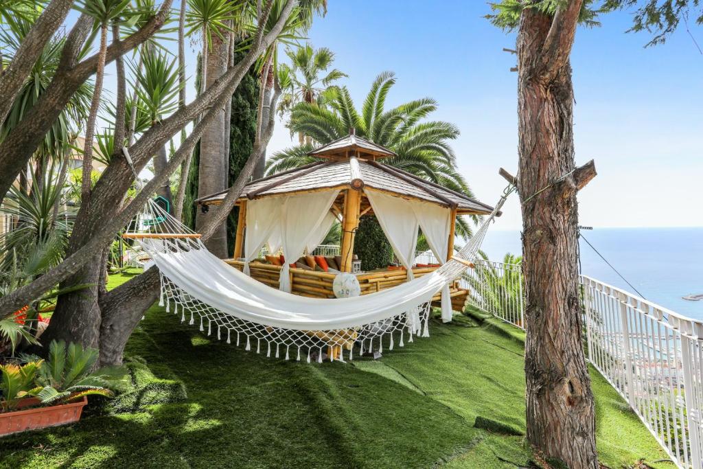 a hammock in a resort with palm trees at Studio en bord de mer à Menton avec piscine privée 80 m² in Menton