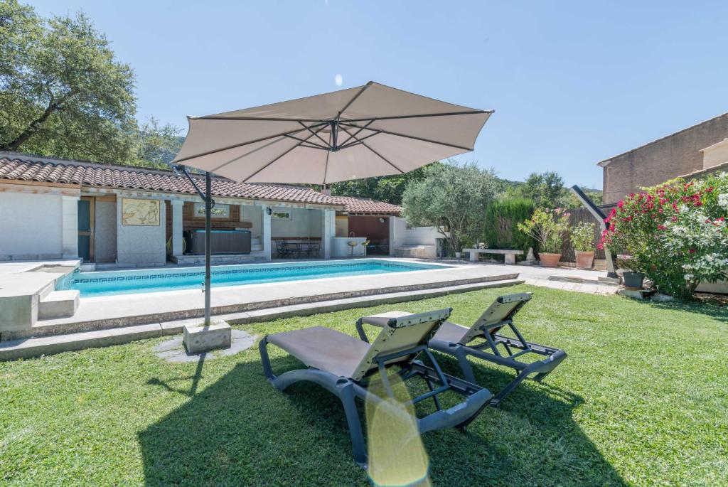 een tuin met 2 stoelen en een parasol naast een zwembad bij Villa de 3 chambres avec piscine privee jacuzzi et jardin amenage a Oppede in Oppède