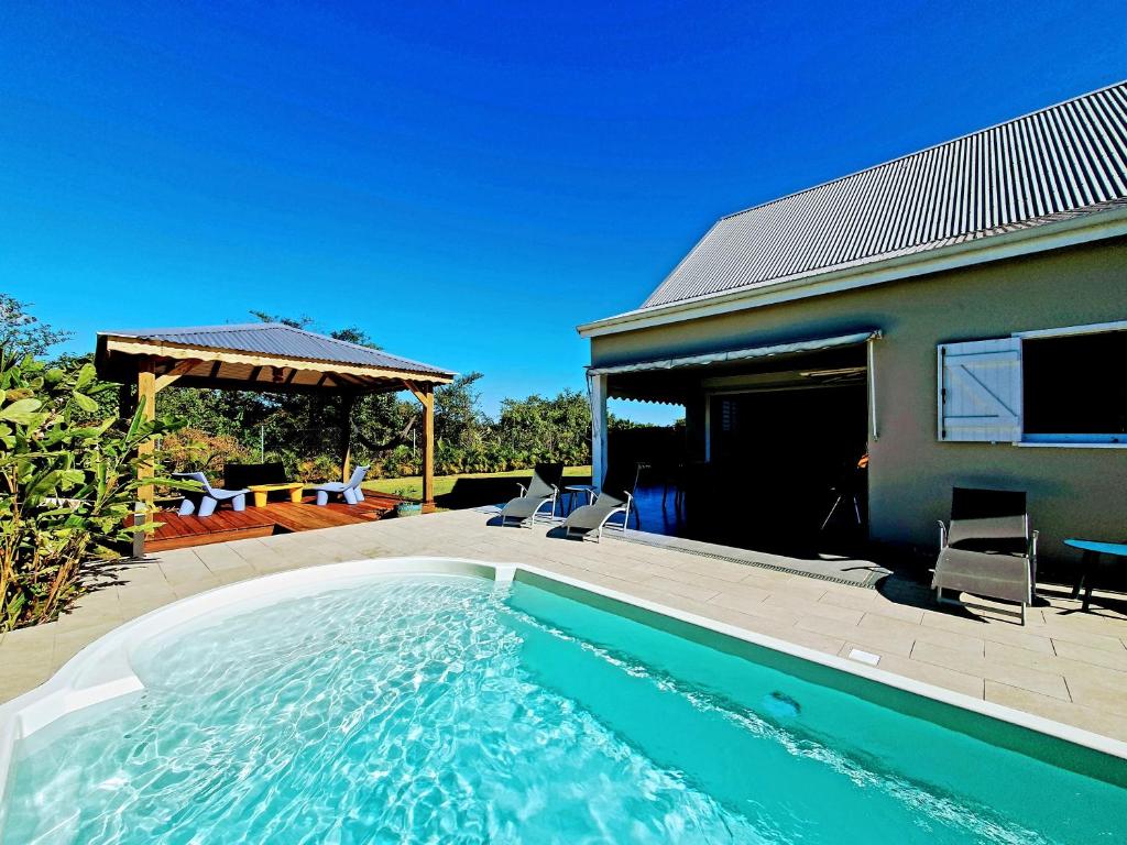 a swimming pool in front of a house at Villa Ohana in Sainte-Anne