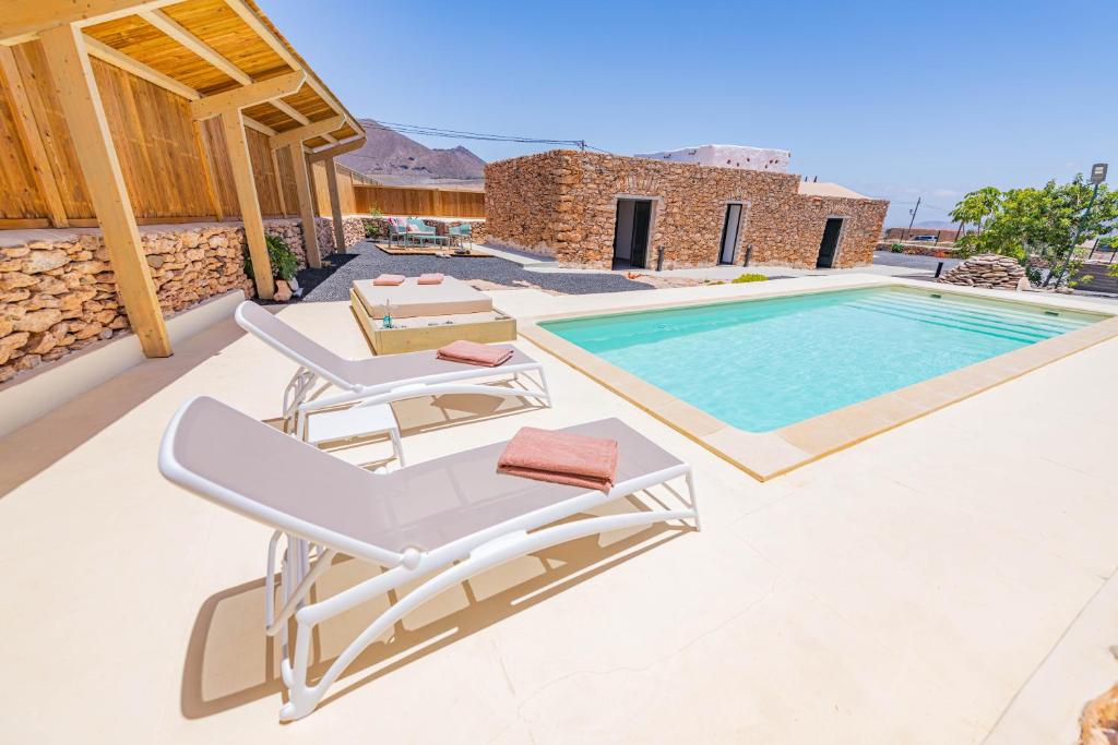 a villa with a swimming pool and two lounge chairs at Casa Rural La Jicara in Tiscamanita