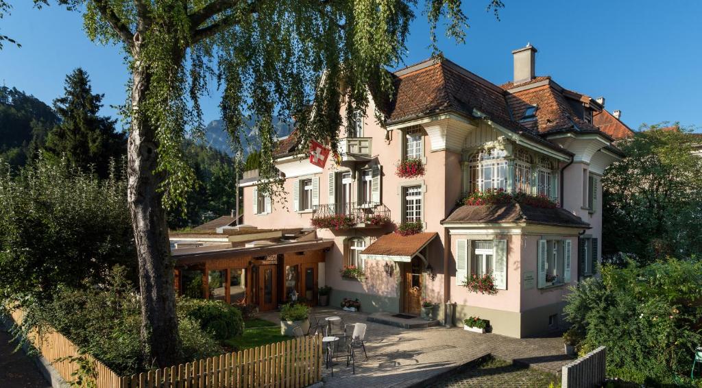 ein großes weißes Haus mit einem Zaun davor in der Unterkunft Swiss Inn & Apartments in Interlaken