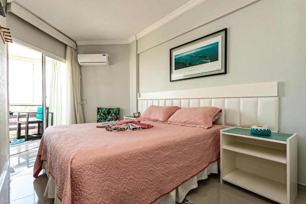 Schlafzimmer mit einem Bett mit rosa Tagesdecke in der Unterkunft Apartamento Ingleses Norte in Florianópolis
