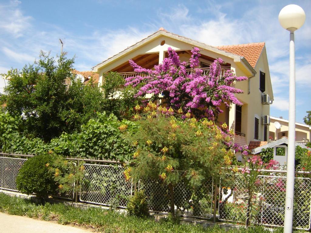 una cerca frente a una casa con flores púrpuras en Apartments Biskup, en Privlaka