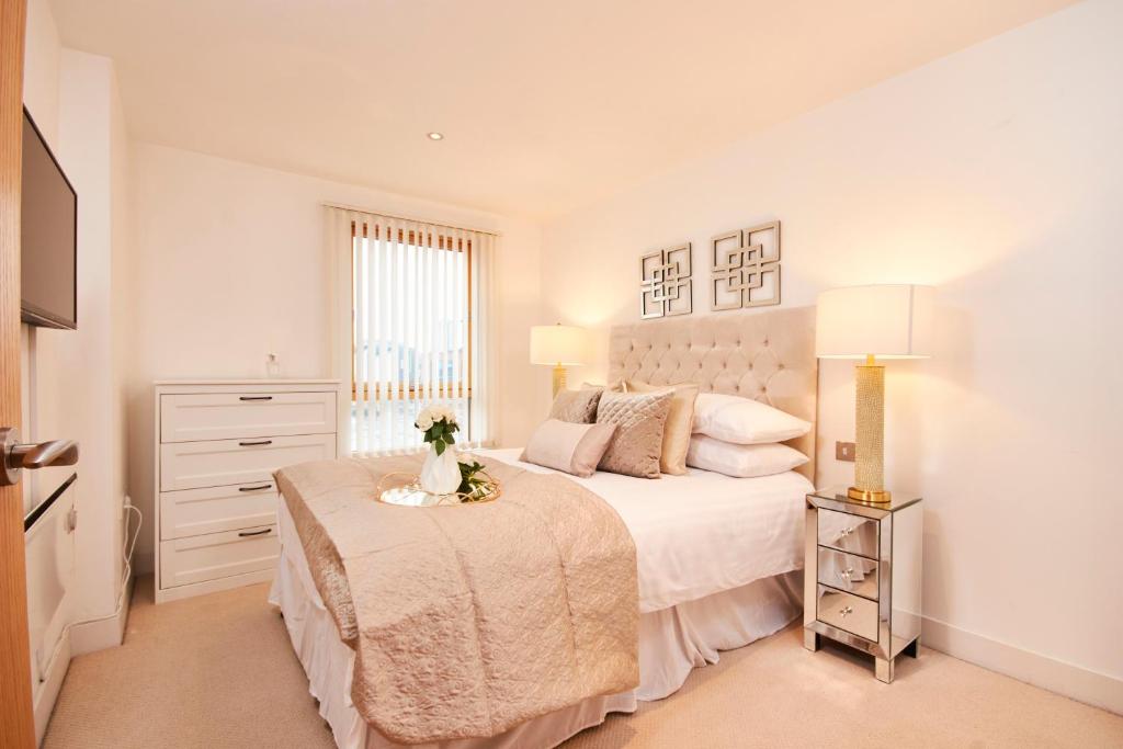a white bedroom with a large bed and a window at Deluxe City Centre Apt Balcony View& Free Parking! in Leeds