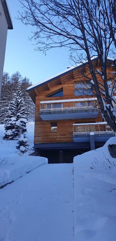 une maison en bois avec un balcon dans la neige dans l'établissement Foux d Allos Centre de la Station 4 Pièces 8 Personnes, à Allos