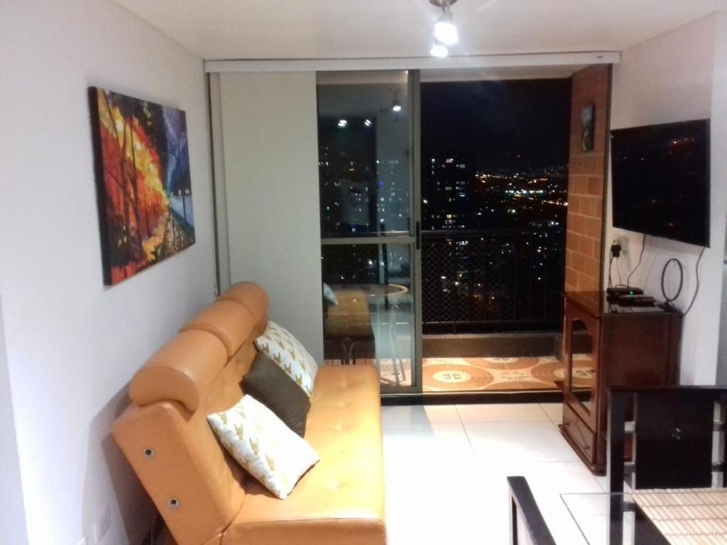 a living room with a couch and a large window at Hermoso y acogedor apartamento en Belén Rodeo Alto in Medellín