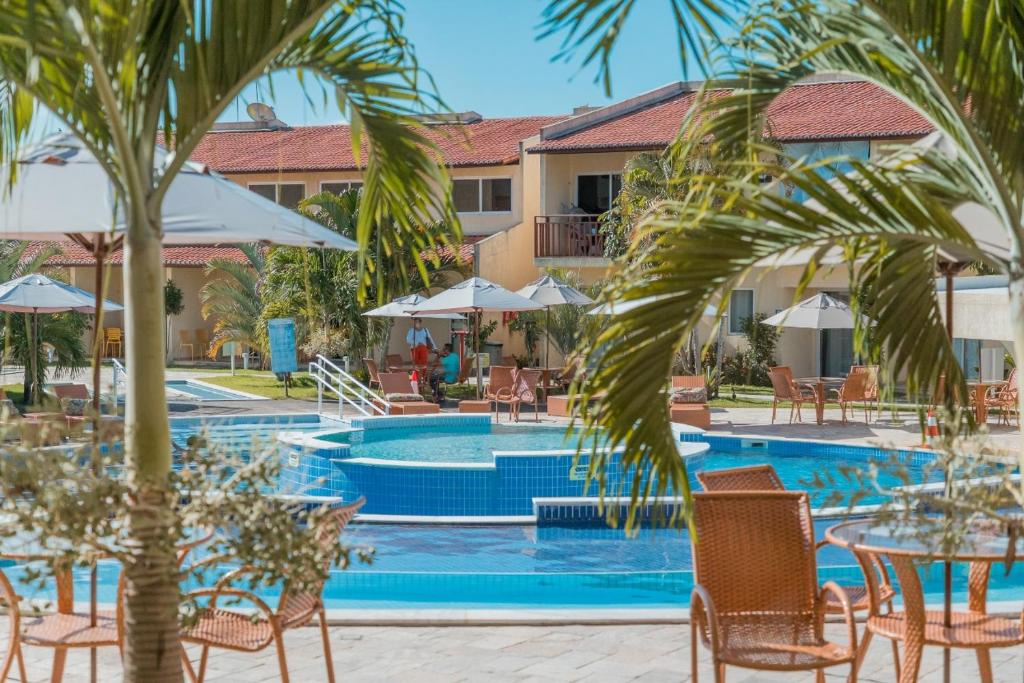 ein Resortpool mit Tischen, Stühlen und einer Palme in der Unterkunft Solar Agua in Pipa