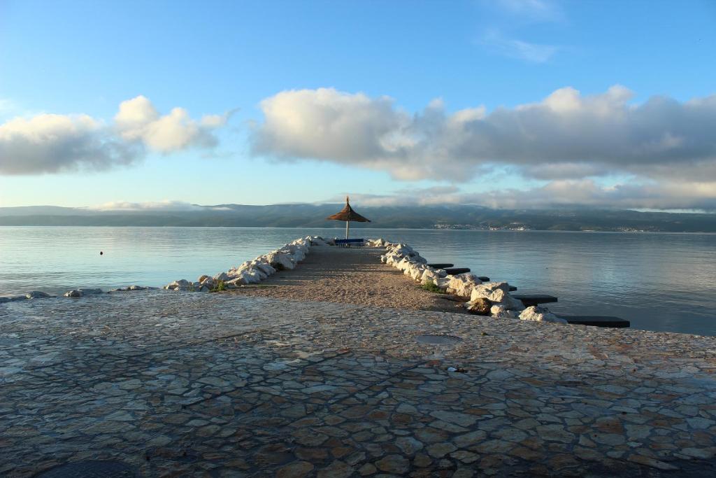 a long pier with an umbrella on the water at Apartments Petrada in Omiš