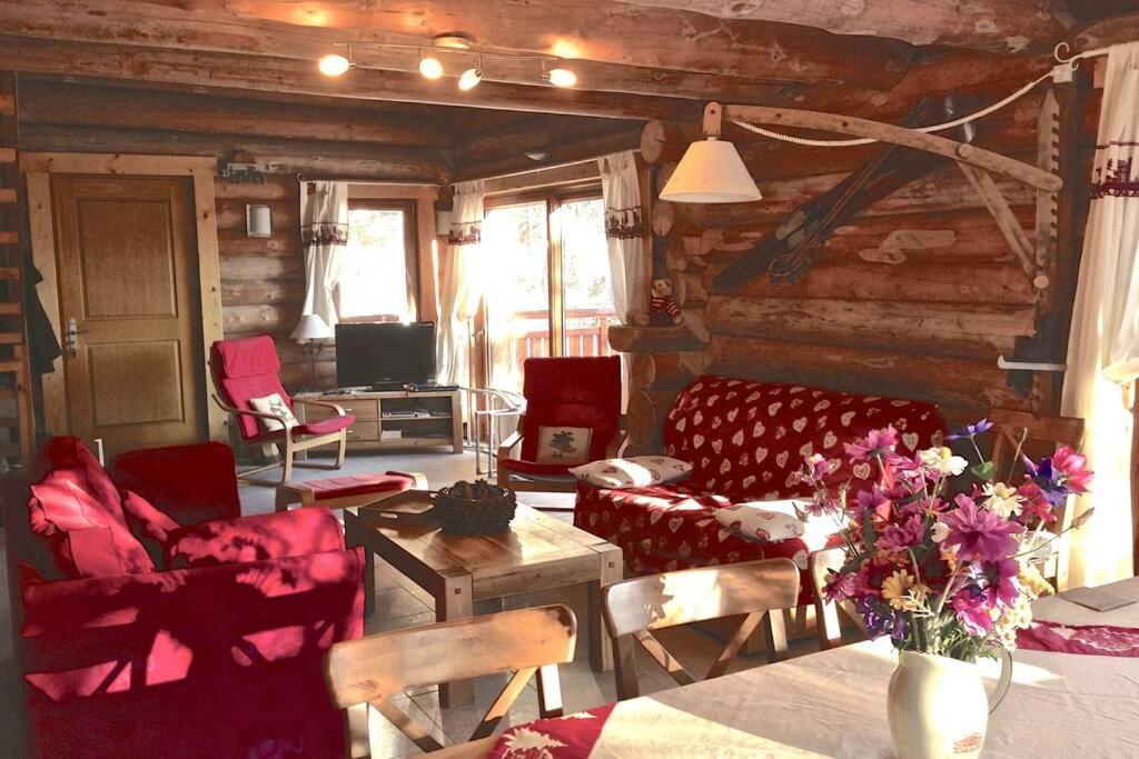 a living room with red chairs and a table with flowers at Chalet les SORBIERS, en rondins, classé 4****étoiles in Bolquere Pyrenees 2000
