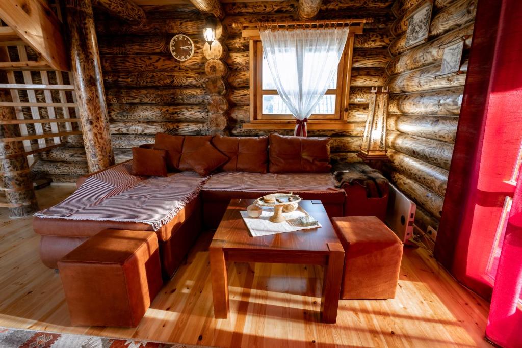 a living room with a couch and a table in a log cabin at Zlatarske brvnare Zlatar Chalets in Nova Varoš